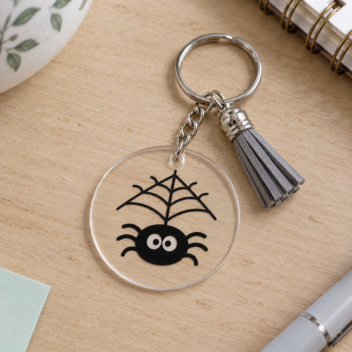 Porte-clés Halloween acrylique transparent araignée noire sur sa toile avec pompon gris